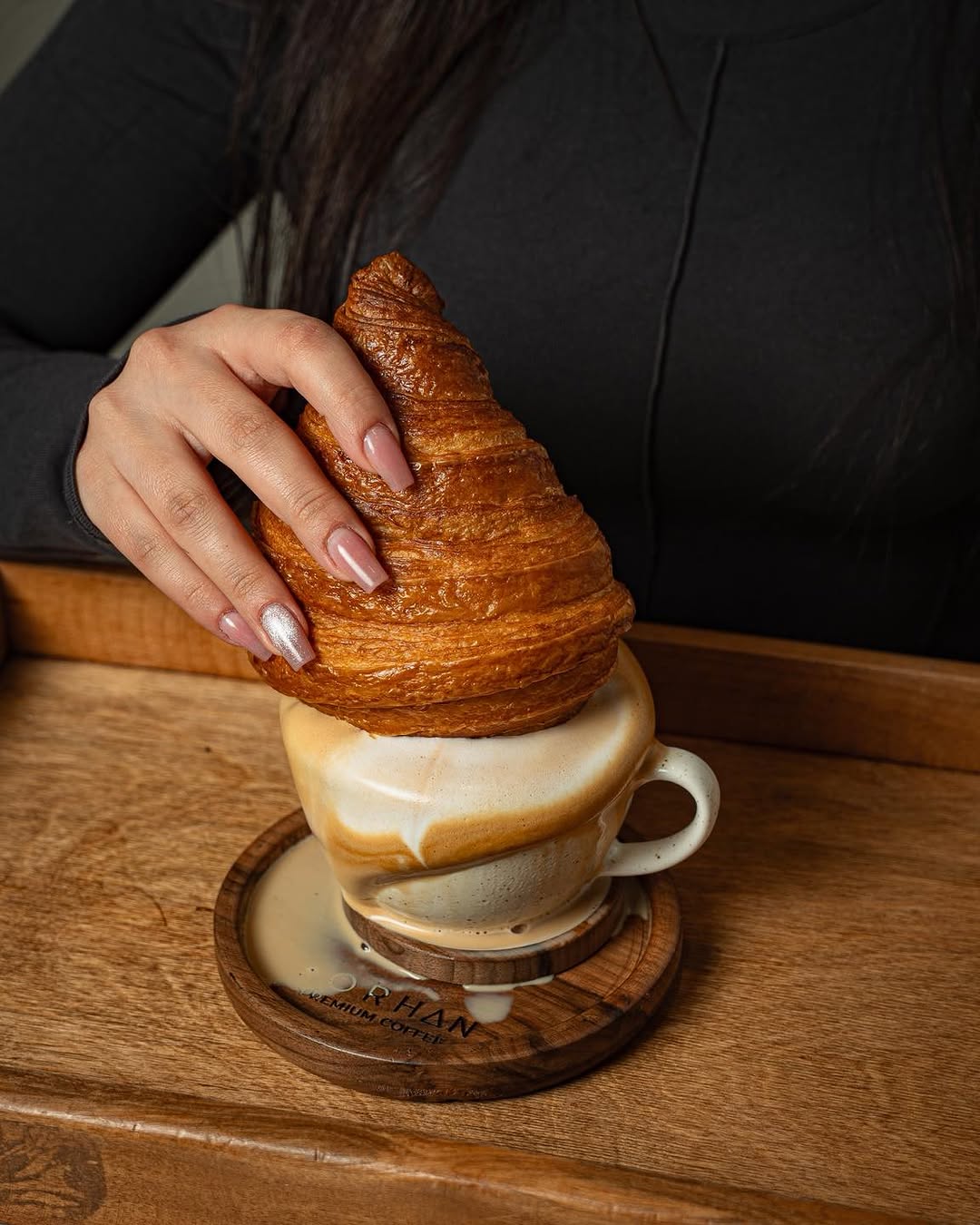 Korhan signature: croissant balanced on a latte cup